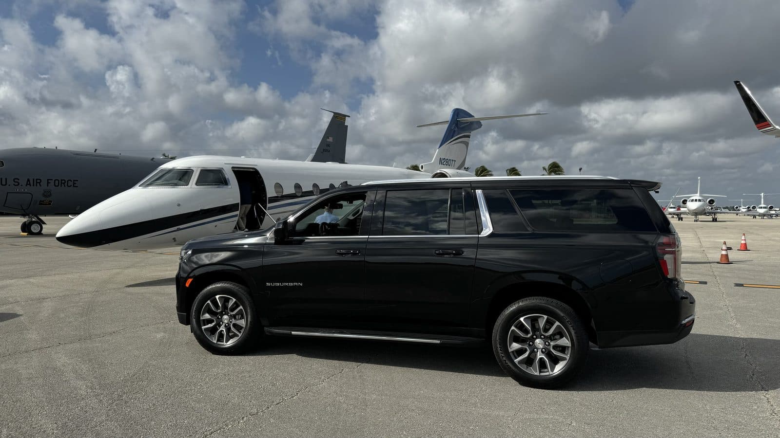 Black Chevrolet Suburban staged beside a private jet in South Florida
