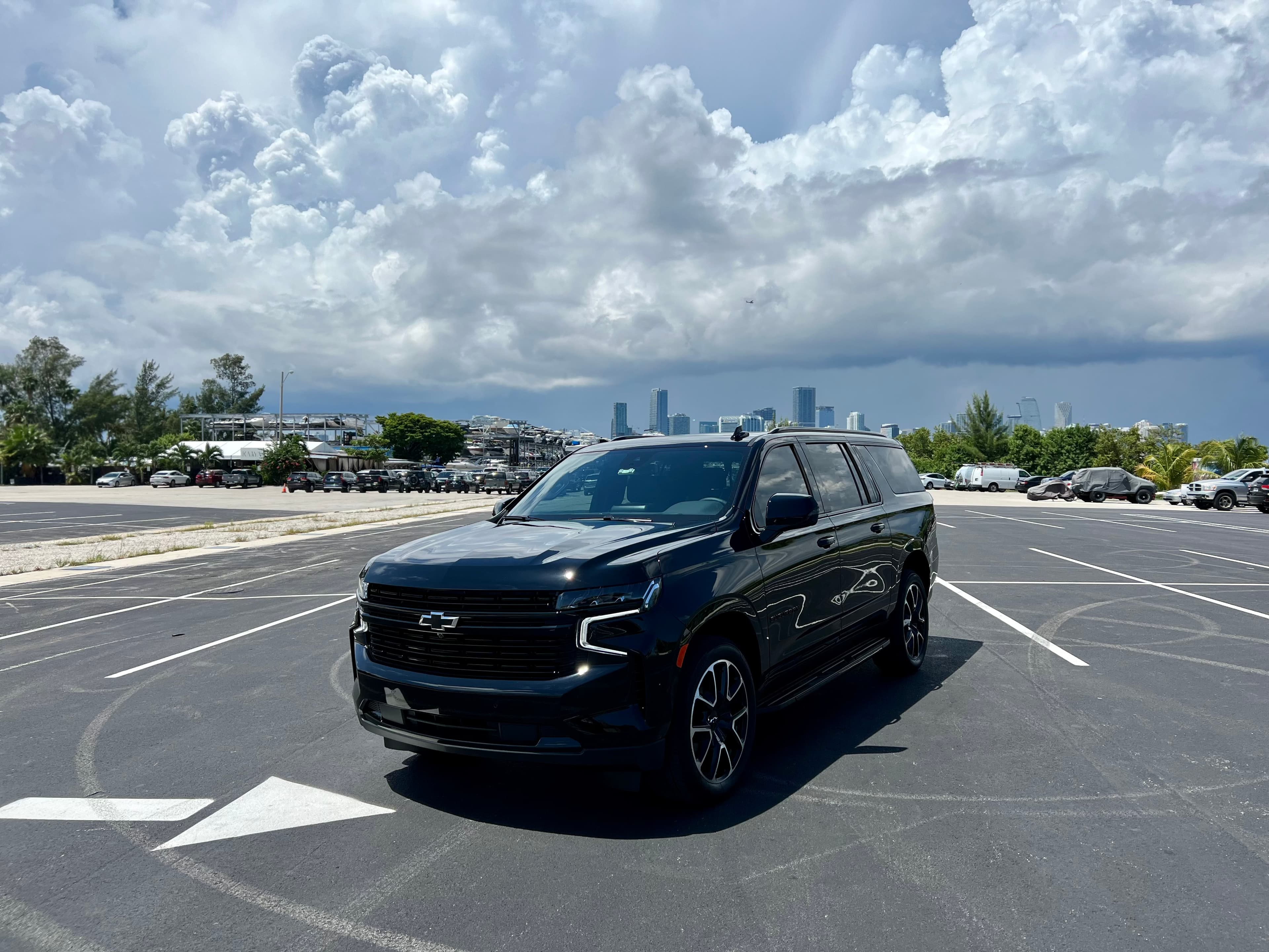 Black Suburban with the Miami downtown skyline behind, midday cool light